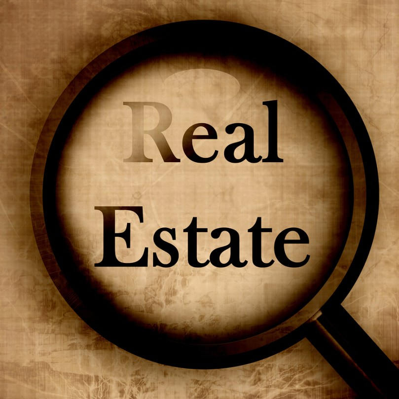 The words Real Estate highlighted under a large magnifying glass